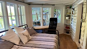 A bedroom with a bed, pillows, a chair, and a desk. - Cozy, renovated rustic cottage on the shore of beautiful navigable lake
 (Labelle)