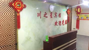 A reception area with a reception desk, a wall with decorative elements, and a checkered pattern on the left.