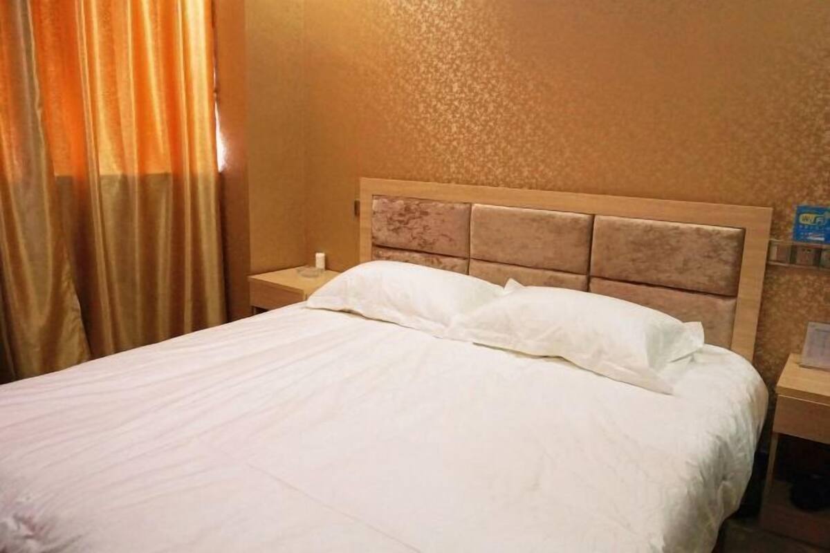 A hotel room with a bed, a nightstand, and a curtain.