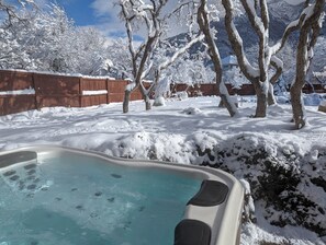 A hot tub surrounded by snow-covered trees and a wooden fence. - Sandy East Bench • Pool • Mountain Views • Hot Tub (Sandy)