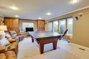 A spacious living room with a pool table, leather sofa, and a television. - Sandy East Bench • Pool • Mountain Views • Hot Tub (Sandy)