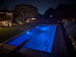 A rectangular swimming pool with a blue light, surrounded by a deck and a house with a balcony. - Sandy East Bench • Pool • Mountain Views • Hot Tub (Sandy)