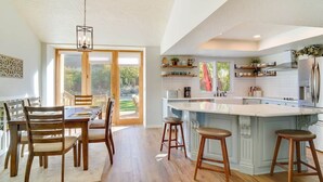 A spacious kitchen with a large island, wooden chairs, and a dining table. - Sandy East Bench • Pool • Mountain Views • Hot Tub (Sandy)