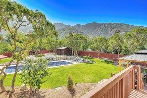 A backyard with a swimming pool, a wooden deck, and a view of mountains. - Sandy East Bench • Pool • Mountain Views • Hot Tub (Sandy)
