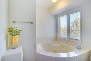 A bathroom with a bathtub, a window with blinds, a towel rack, and a plant. - Sandy East Bench • Pool • Mountain Views • Hot Tub (Sandy)