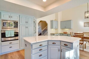A kitchen with light blue cabinets, a large island, and a built-in microwave.