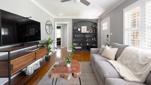 Un salon équipé d’un téléviseur à écran plat, d’une table basse en bois, d’un canapé et d’un ventilateur de plafond.