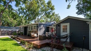 Une maison avec une terrasse, un espace salon extérieur et un hamac.