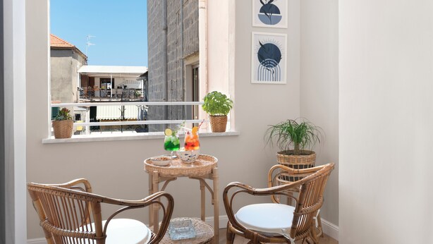 A balcony with wicker chairs, a small table with drinks, and potted plants. - Maison MimìMarì - Sorrento City Center (Sorrento)