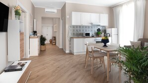 A modern kitchen with white cabinets, a wooden dining table, and a built-in microwave. - Maison MimìMarì - Sorrento City Center (Sorrento)