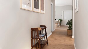 A hallway with wooden flooring, a bookshelf, framed artwork, and a door leading to another room. - Maison MimìMarì - Sorrento City Center (Sorrento)