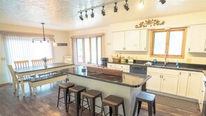 A spacious kitchen with a central island, bar stools, and a dining table.