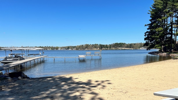A lakeside beach with a dock, benches, and a picnic table.