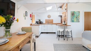 Una cocina moderna con armarios blancos, una encimera de madera y un comedor con mesa y sillas de madera.