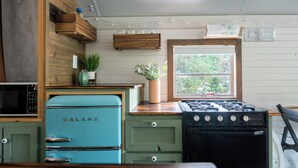 A compact kitchen with a Galanz refrigerator, a stove, and a microwave. - The Pinnacle Mountain Bus Stop ~ Fire pit, Frisbee Golf, Baggo, Hammock (Little Rock)
