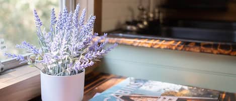 A kitchen area with a window, a potted lavender plant, and a magazine on the windowsill.