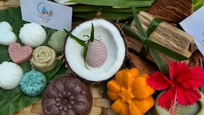 A variety of colorful, heart-shaped chocolates arranged on a woven mat, surrounded by coconuts and green leaves. - Naupamanta Pacha (Chazuta)