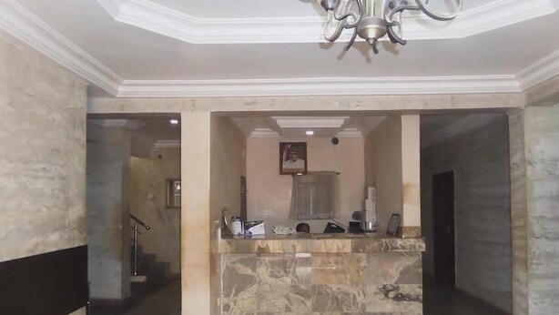 A lobby with a reception desk, marble flooring, and a chandelier. - Chinox Guest Inn (Abuja)