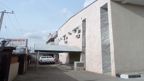 A guest parking area with a white pickup truck, a covered parking structure, and a building with a sign for 'Chinox Guest Inn'. - Chinox Guest Inn (Abuja)
