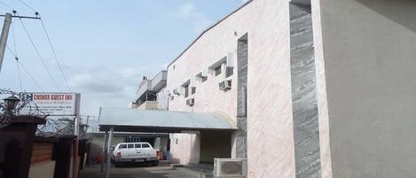 A guest parking area with a white pickup truck, a covered parking structure, and a building with a sign for 'Chinox Guest Inn'.
