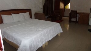 A hotel room with a large bed, a desk, and a chair. - Chinox Guest Inn (Abuja)