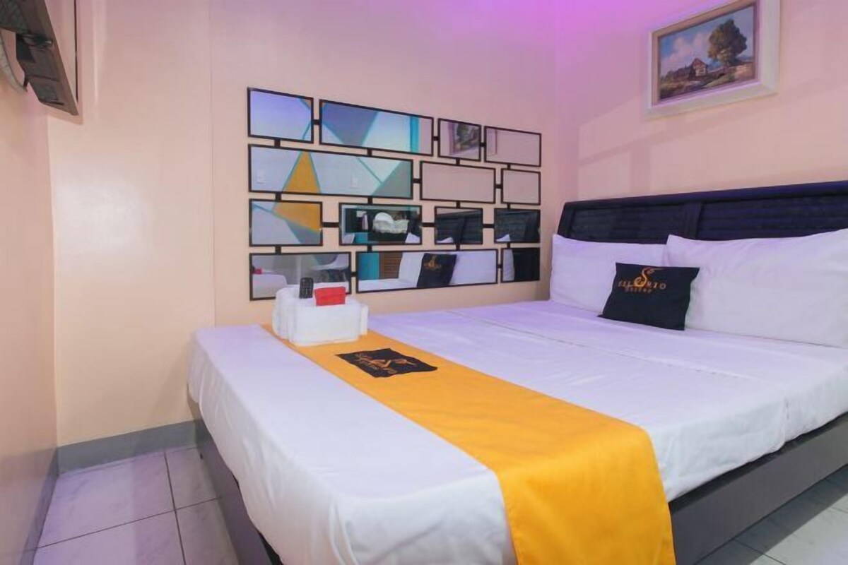 Une chambre d’hôtel avec un lit, une table de chevet, une œuvre d’art murale et un tableau encadré accroché au mur.