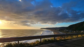 A coastal road with a guardrail, ocean waves, and a hilly landscape in the background. - Oceana Suites Curiñanco (Valdivia)
