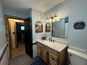 A bathroom with a wooden vanity, a large mirror, and a sign that reads "THE best seat IN THE HOUSE". - Newly remodeled, fully equipped house close to many LAKES and TRAILS! (Cass Lake)