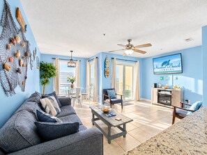 A spacious living area with a sofa, coffee table, and a television displaying 'Navarre Beach Landing'.