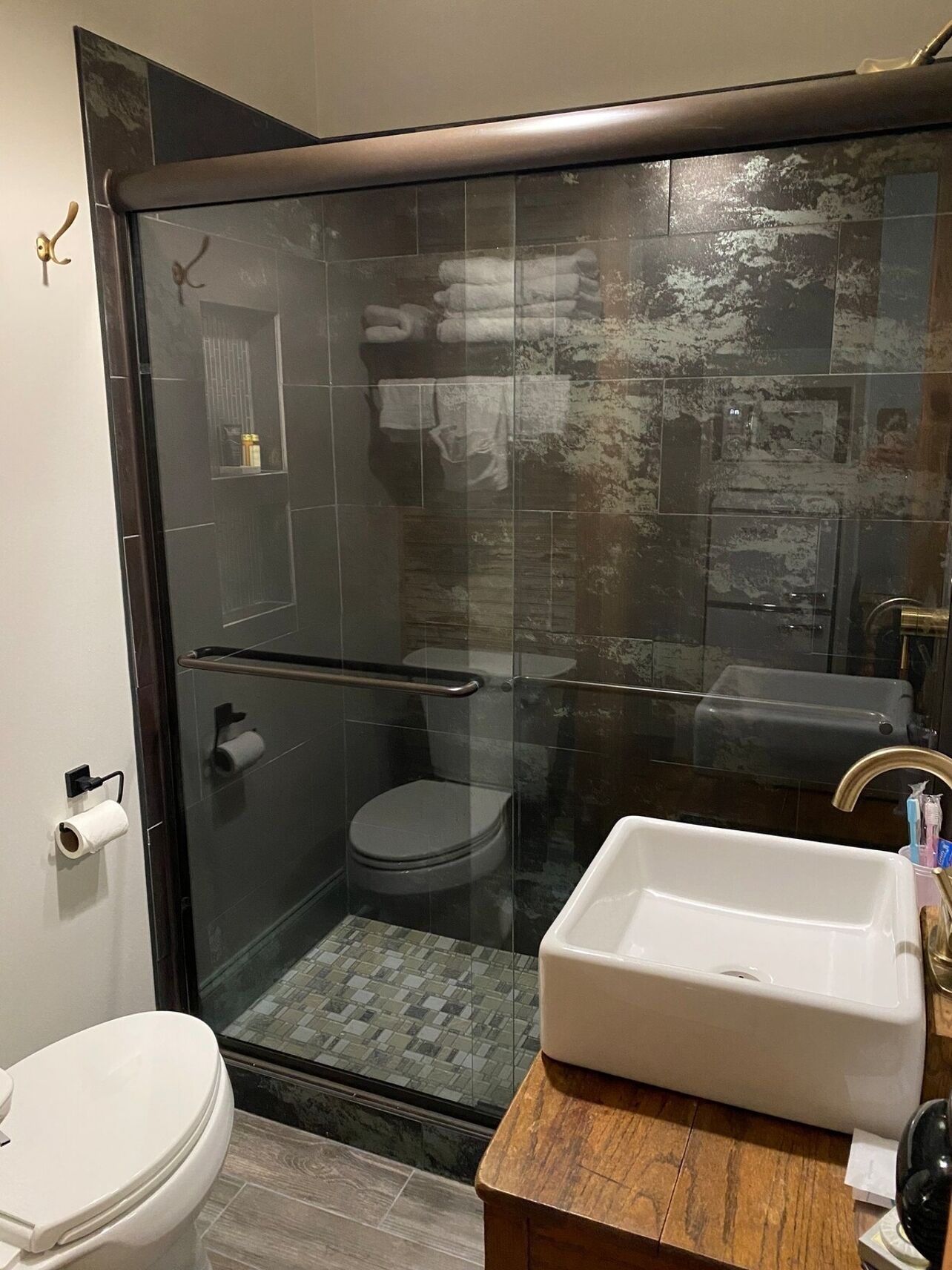 Un bany modern amb dutxa de vidre, un lavabo blanc i un vàter.