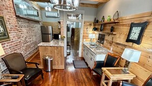 A cozy kitchen with wooden beams, a central island, and a dining area with chairs and a table. - Room 5 (sleeps 2) at Chipley's Squareview Inn (Carthage)