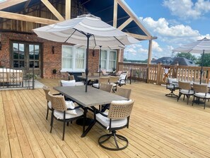An outdoor patio with a wooden deck, a table with chairs, and a large umbrella. - Room 5 (sleeps 2) at Chipley's Squareview Inn (Carthage)