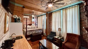 A cozy room with a wooden ceiling, a bed with a canopy, a dining table, a sofa, and a chair. - Room 7 (sleeps 2) at Chipley's Squareview Inn (Carthage)