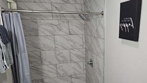 Un bagno moderno con doccia, WC e una pianta in vaso.