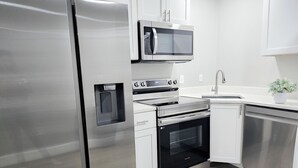 Una cucina moderna con elettrodomestici in acciaio inossidabile, tra cui frigorifero, microonde, forno e lavastoviglie.