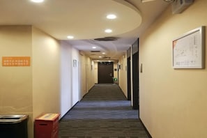 Ein Hotelgang mit Teppichboden, einem Mülleimer und einem an der Wand befestigten Schild.