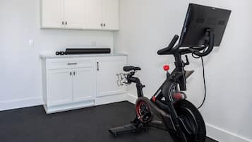 A stationary bike with a digital display, a white cabinet with drawers, and a black floor.