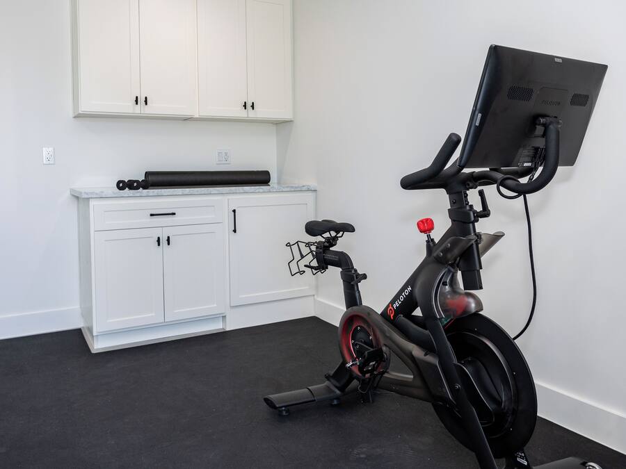 A stationary bike with a digital display, a white cabinet with drawers, and a black floor.