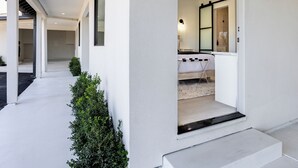 A modern hotel entrance with a clean, white exterior, a visible number '14' on the wall, and a glimpse of a well-lit interior with a bed and a bathroom. - Hotel Bayit Modesto Salida (Salida)