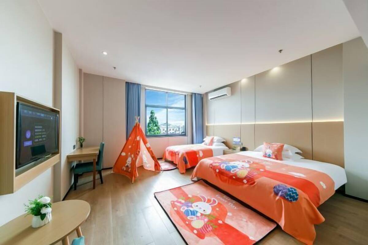 Una camera d'albergo con due letti, una scrivania, una sedia, una televisione e una finestra vista.