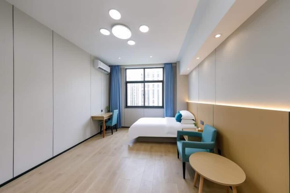Una camera d'albergo moderna con un letto, una scrivania e un angolo salotto.
