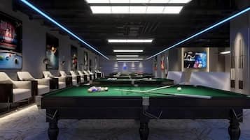 A pool table with balls, a sofa, and a TV screen in a room with a marble floor and blue lighting.