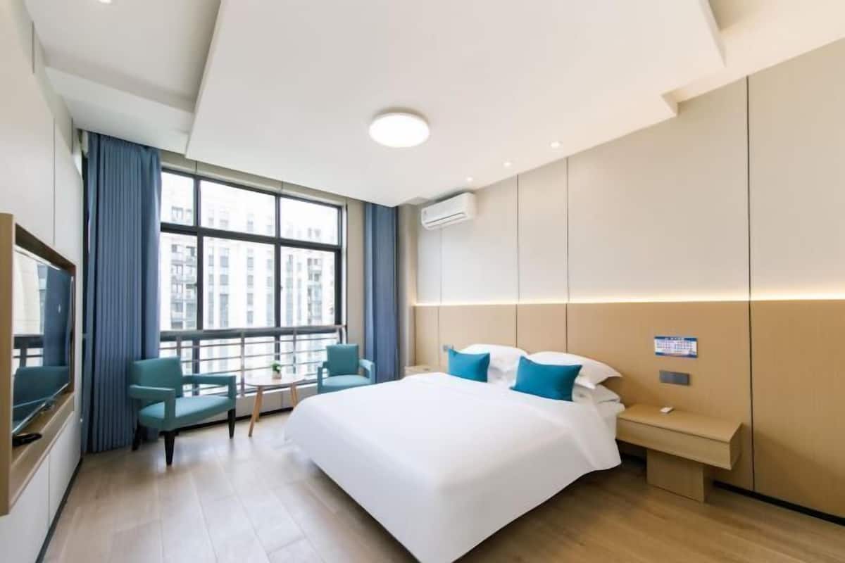 Una moderna camera d'albergo con un letto grande, una scrivania, una sedia e una finestra con tende.