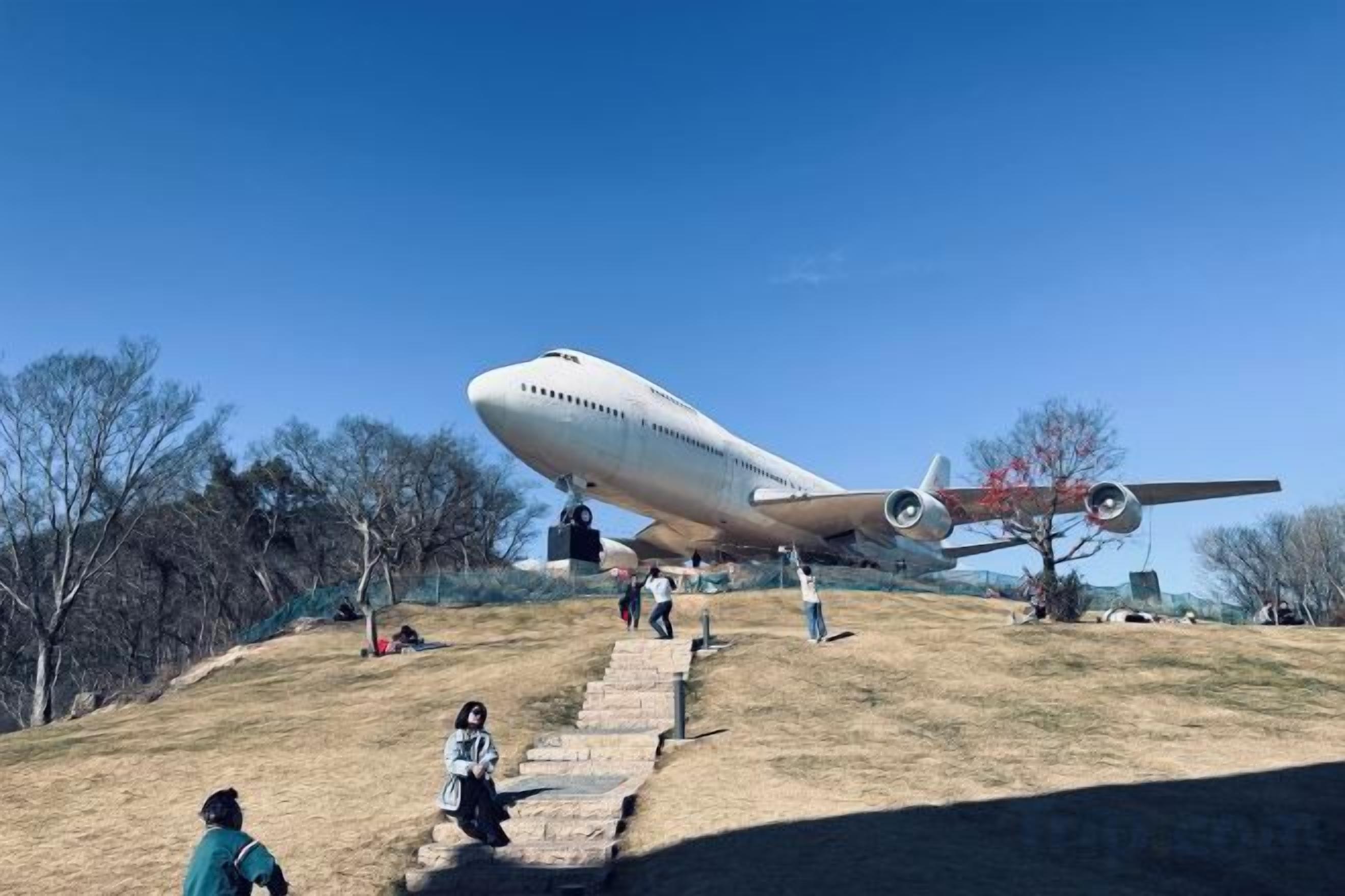 A large airplane parked on a grassy hill with steps leading up to it.