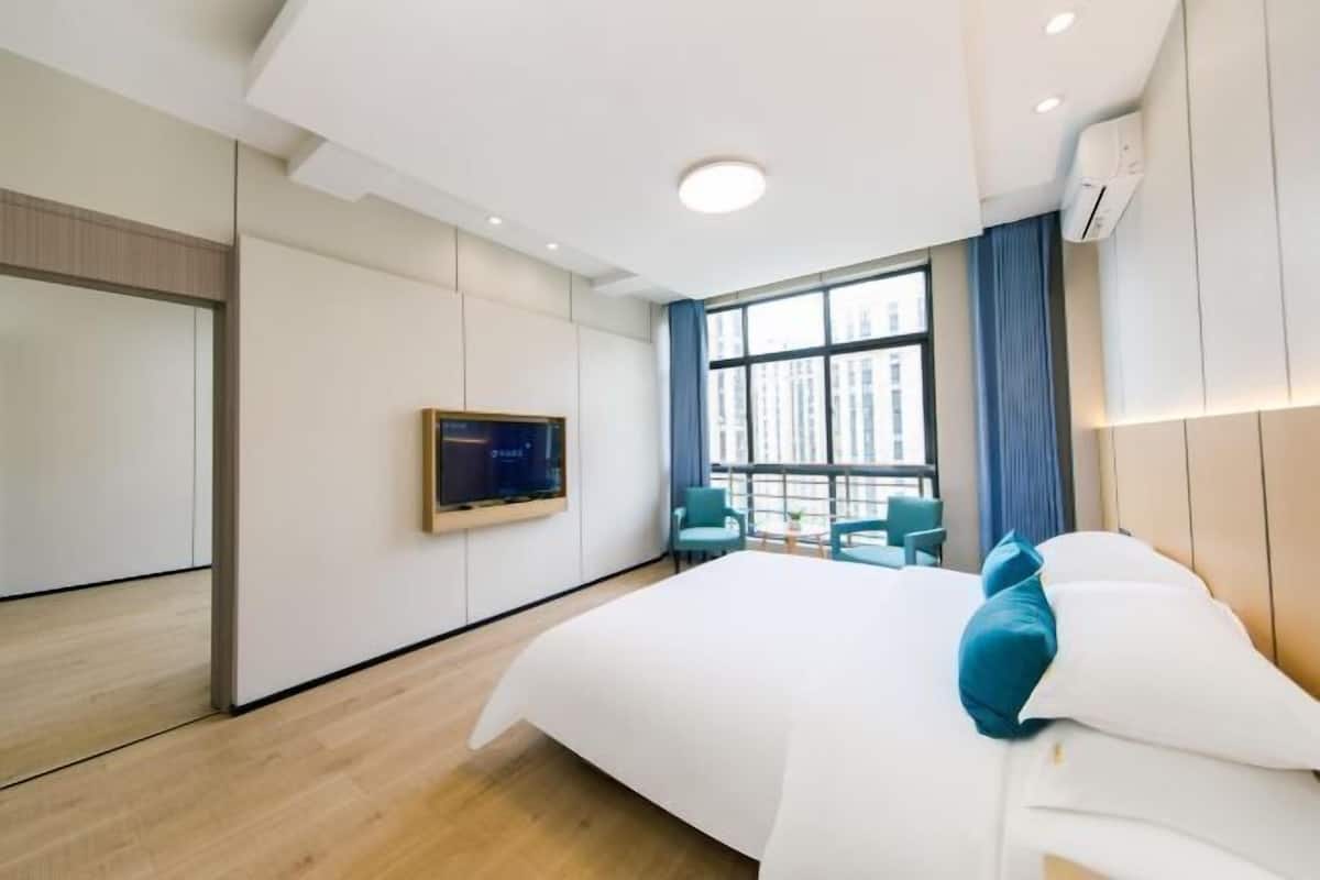 Camera d'albergo moderna con un letto grande, una TV a parete e vista sulla città dalla finestra.