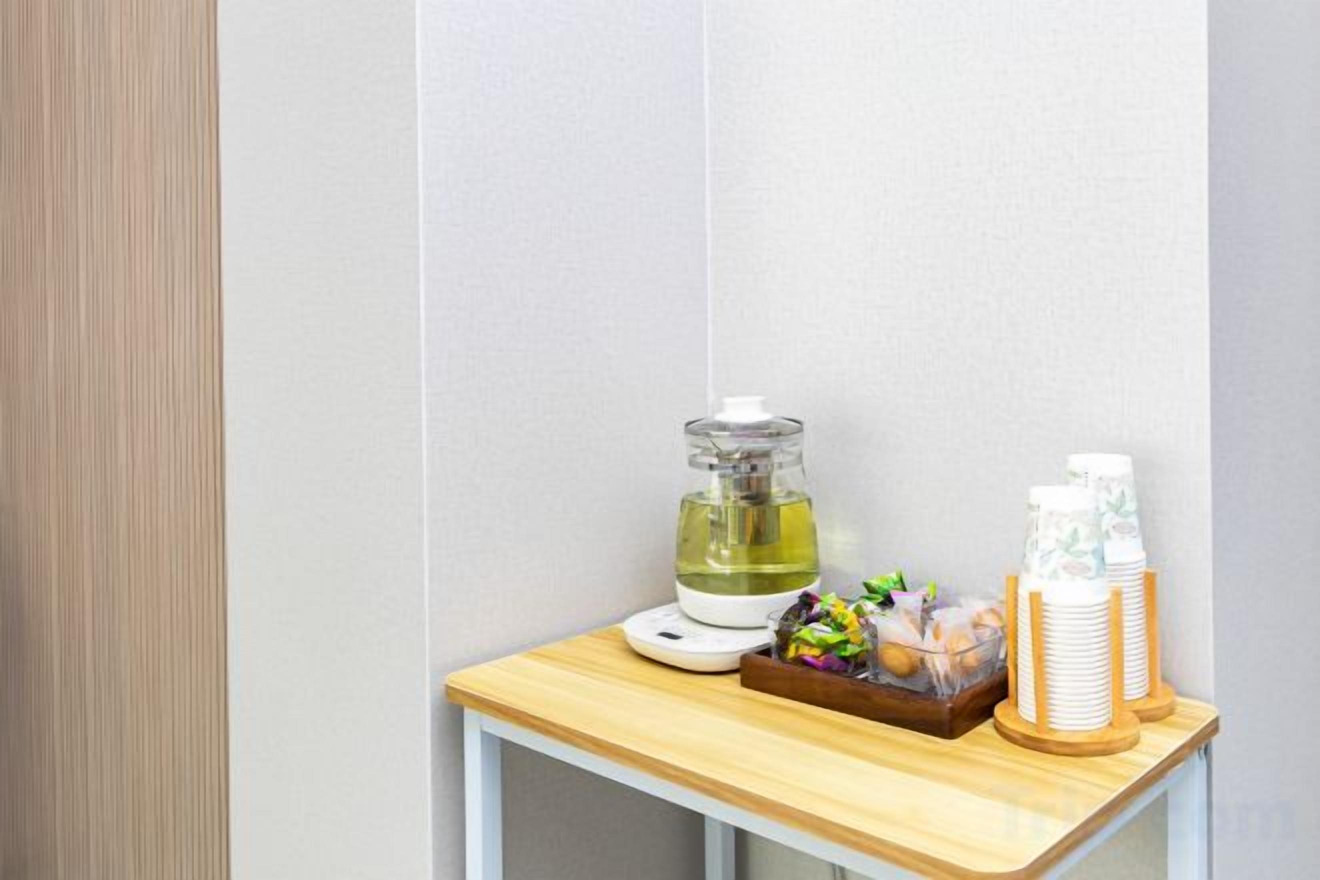 A small wooden table with a water dispenser, a bottle of water, and a tray with snacks.