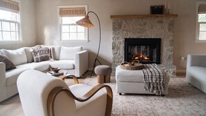 A cozy living room with a stone fireplace, a sofa set, and a floor lamp.