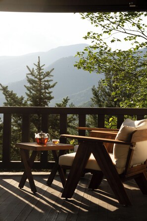Eine Holzdar Terrasse mit Tisch und Stuhl, mit Blick auf eine Berglandschaft.