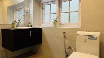 Ein Badezimmer mit Toilette in Weiß, einem schwarzen Waschtisch, einem Fenster mit Aussicht und einer Duschkabine.