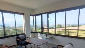 A sunlit room with a large window, a sofa, a table, and a chair. - AKKAYALAR AERIE HOUSE (Bolu)